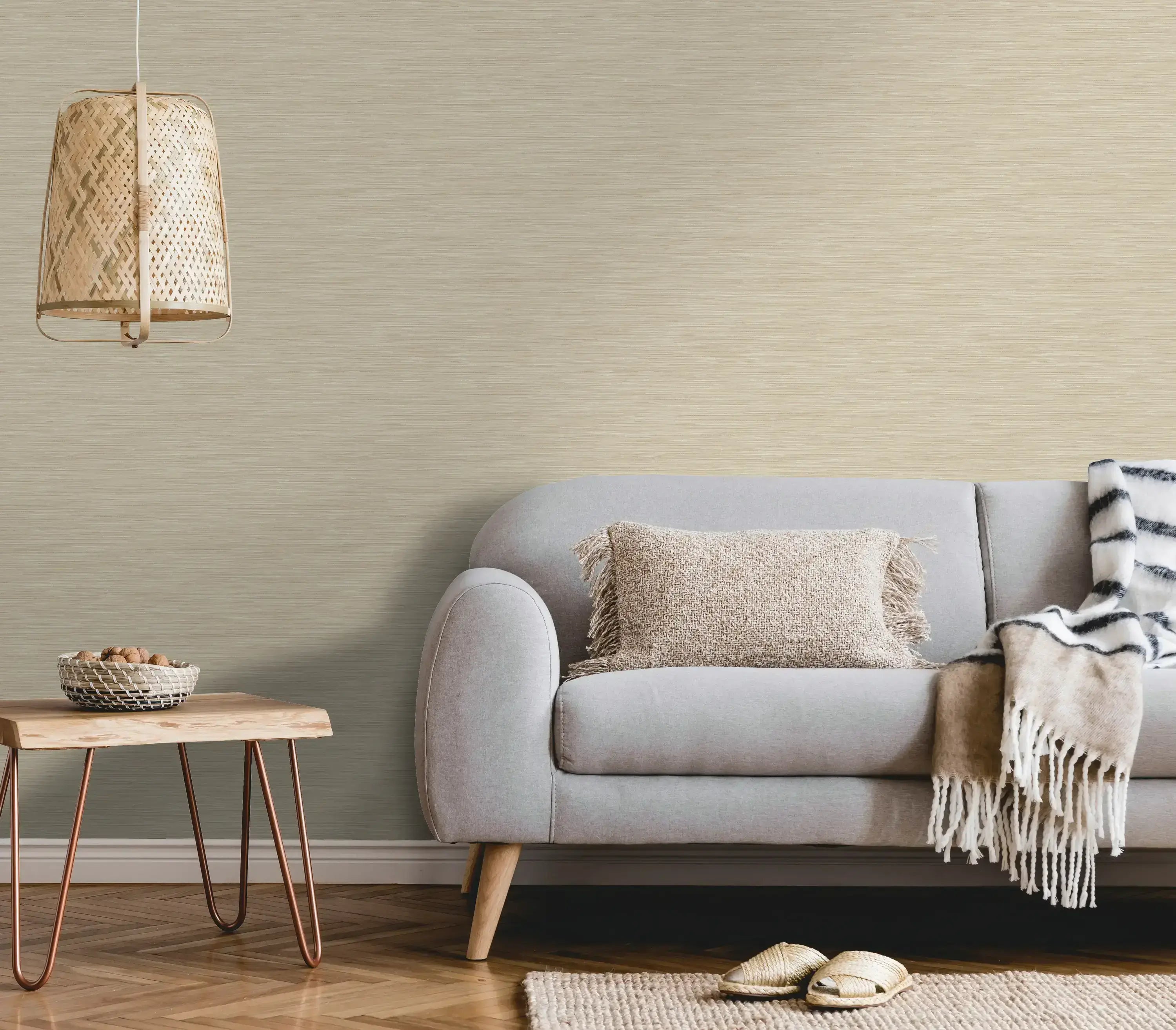 Stue med Bambara Texture - Taupe tapet på væggen. Værelset er indrettet med en grå sofa, en neutral pude, og naturligt træbord.