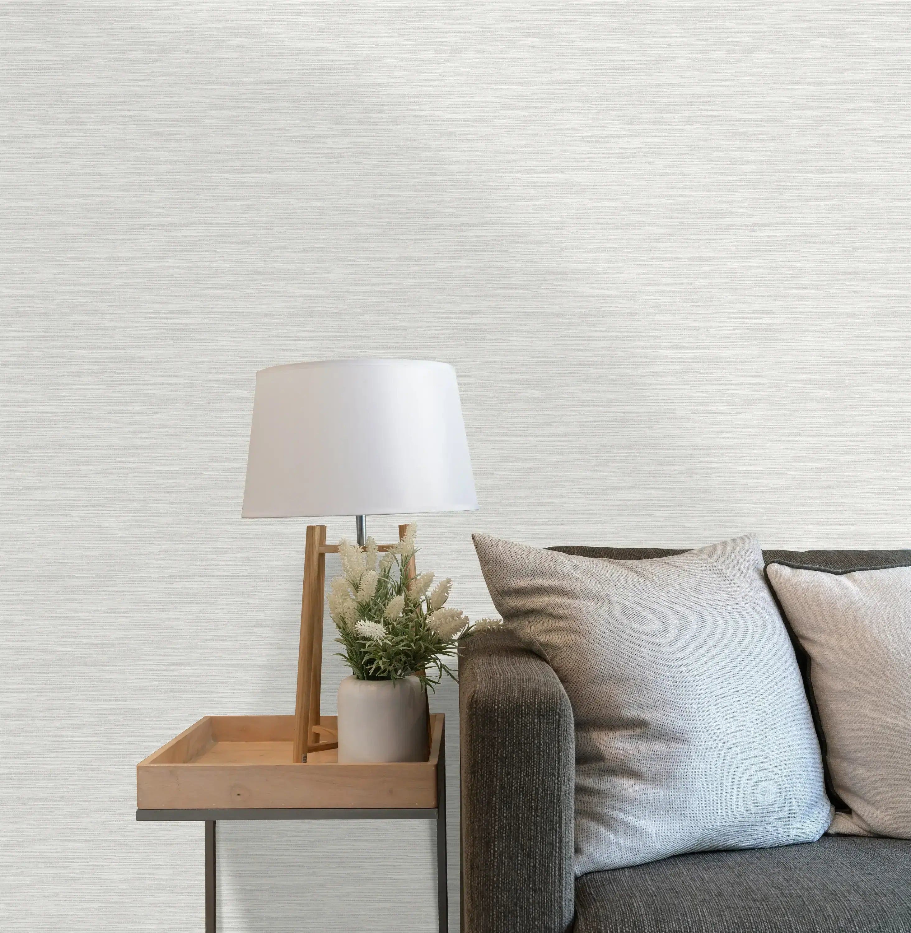 Værelse med Bambara Texture - White tapet, dekoreret med en sofa, bordlampe og blomster, der fremhæver tapetets elegance.