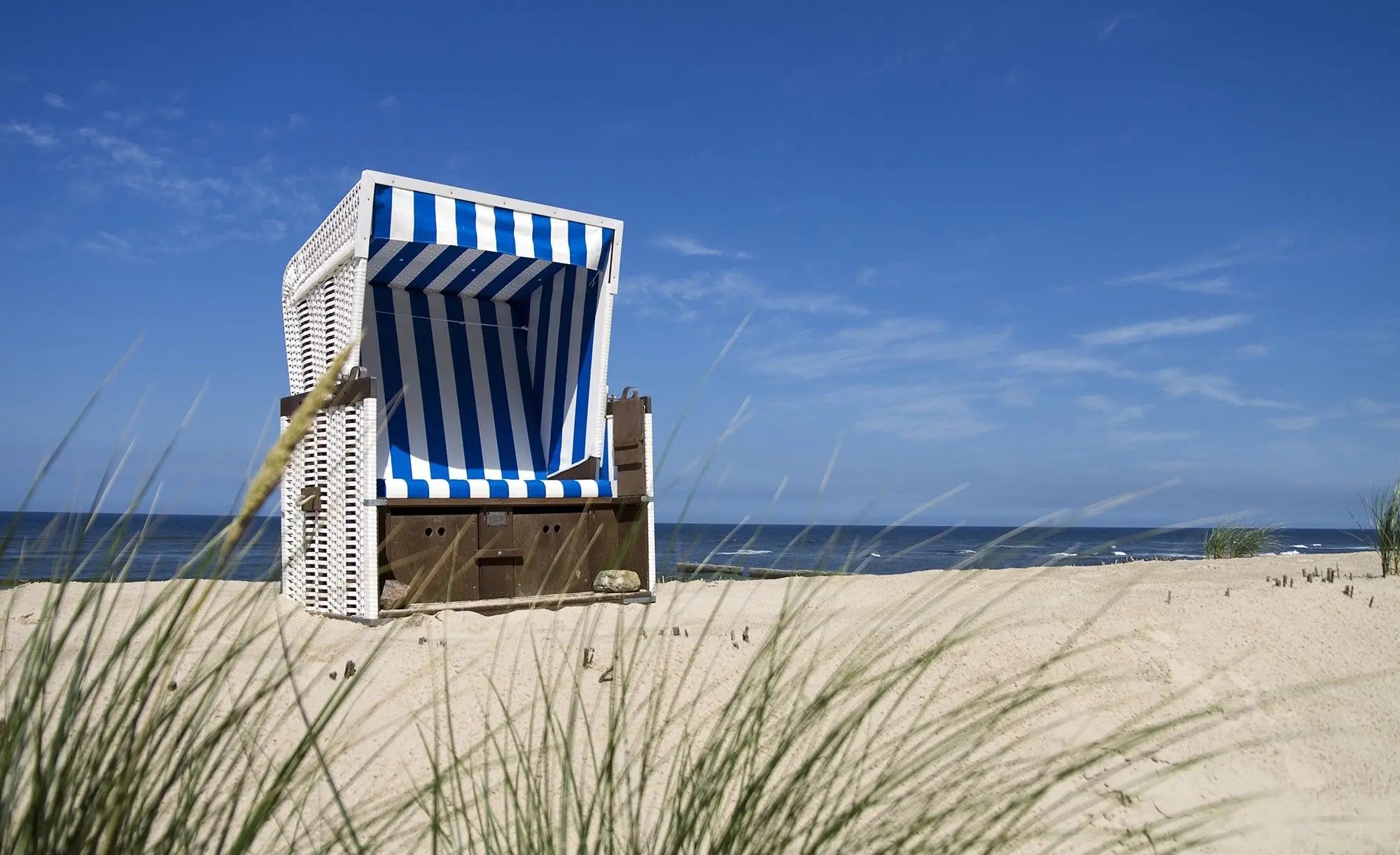 Billede 1 af Fototapet - Blå og hvidstribet strandkurv på sandstrand med havudsigt