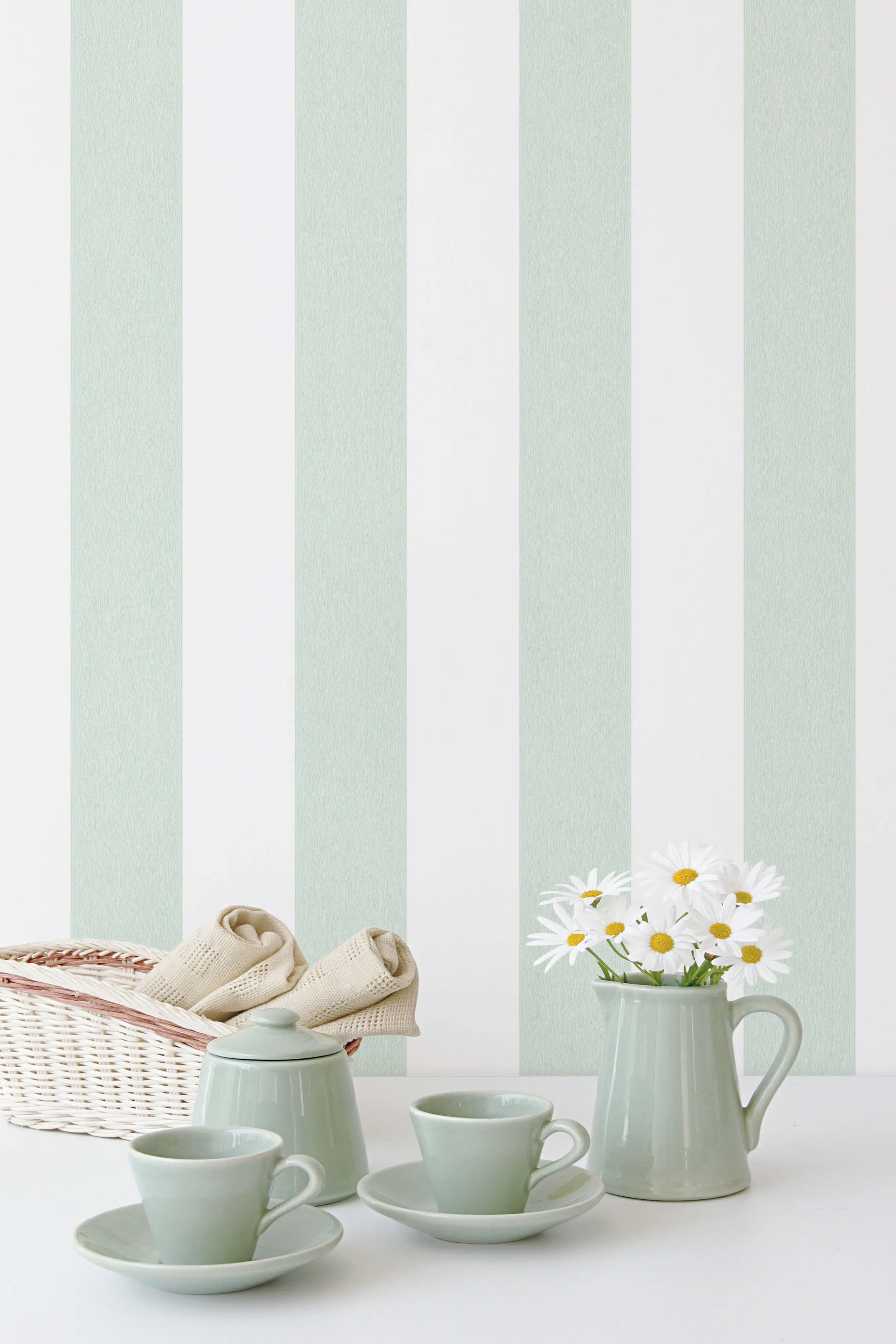 Interiør med Block Stripes - Mint tapet fra Nicetapet.dk, lysegrøn og hvid stribet bag en opstilling af keramik og blomster.