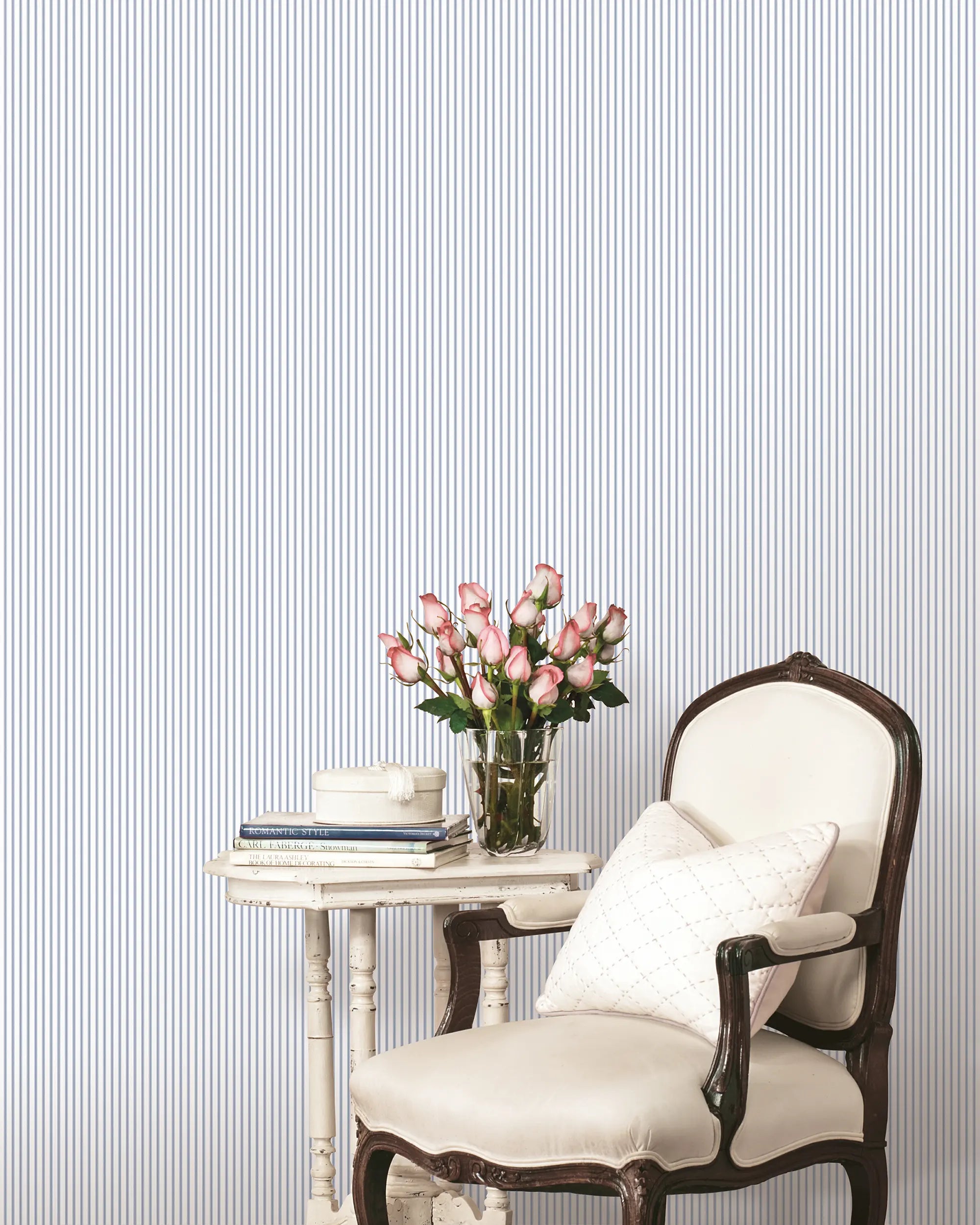 Stue med Elegant Lines - Sky Grey tapet, der har lodrette striber. En hvid stol og et bord med blomster er inkluderet.