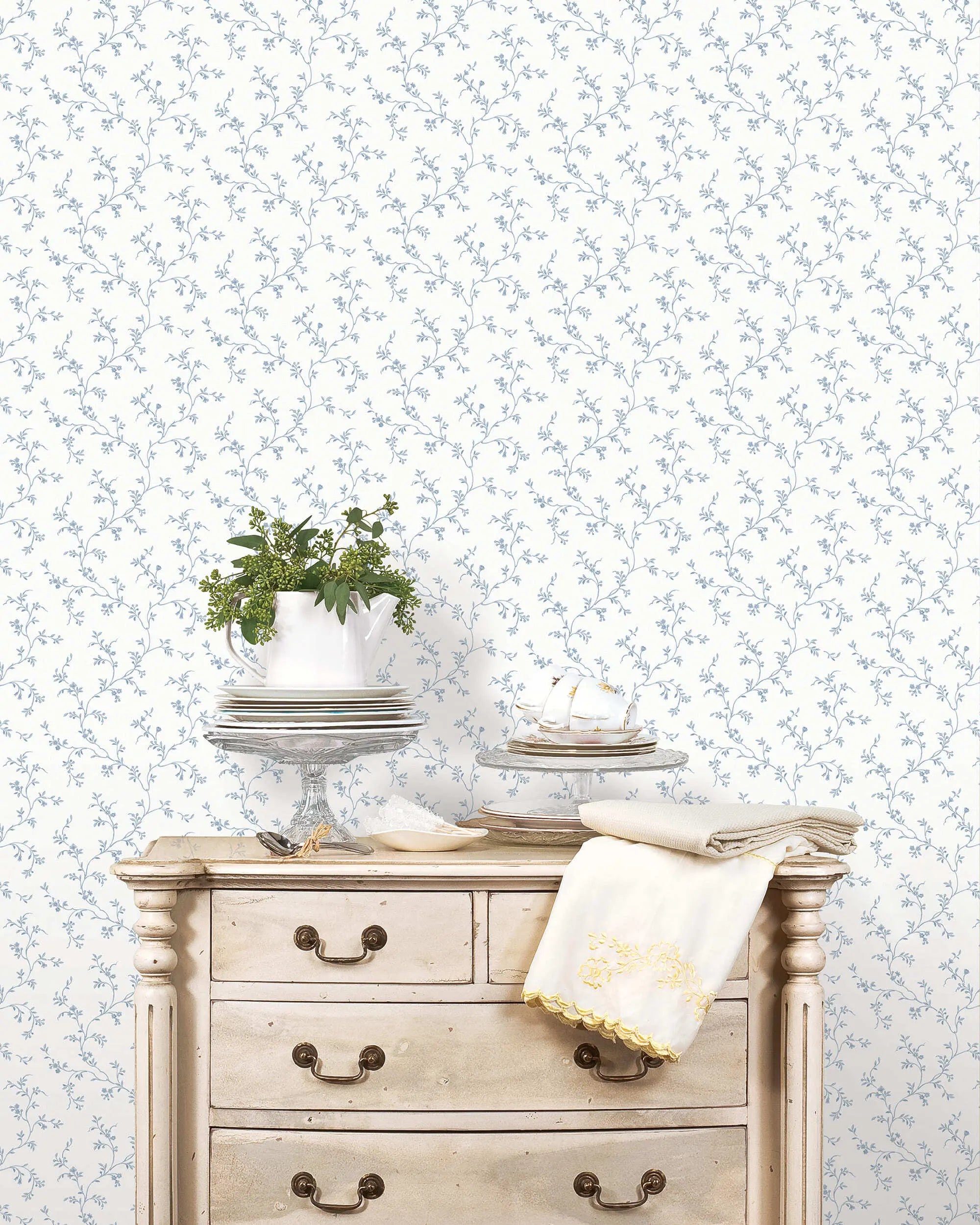 Stilfuld interiør med Floral Silhouette - Misty Sky tapet bag en klassisk kommode dekoreret med tallerkner og planter.