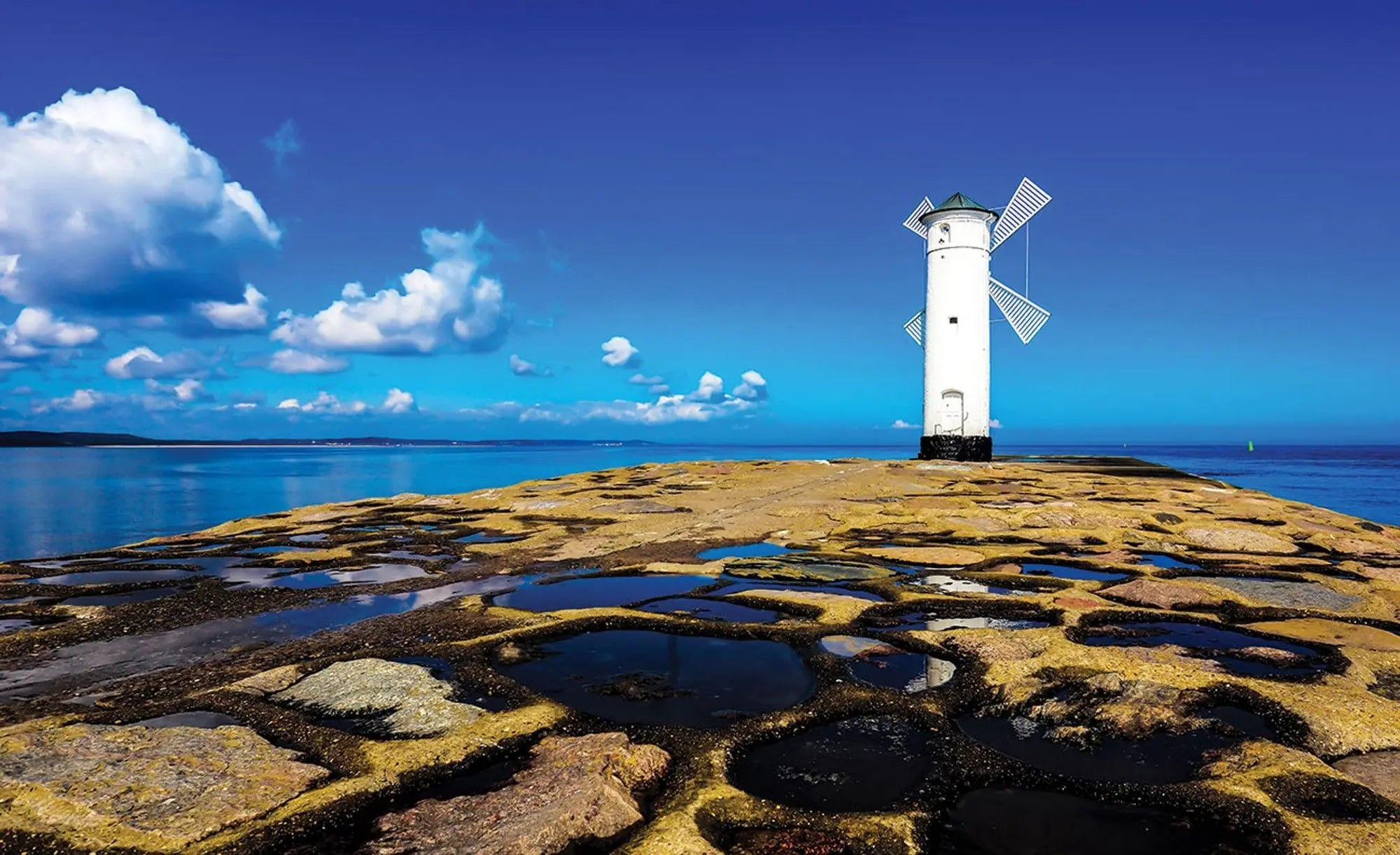 Billede 1 af Fototapet - Hvidt fyrtårn på stenmole ved havet under blå himmel