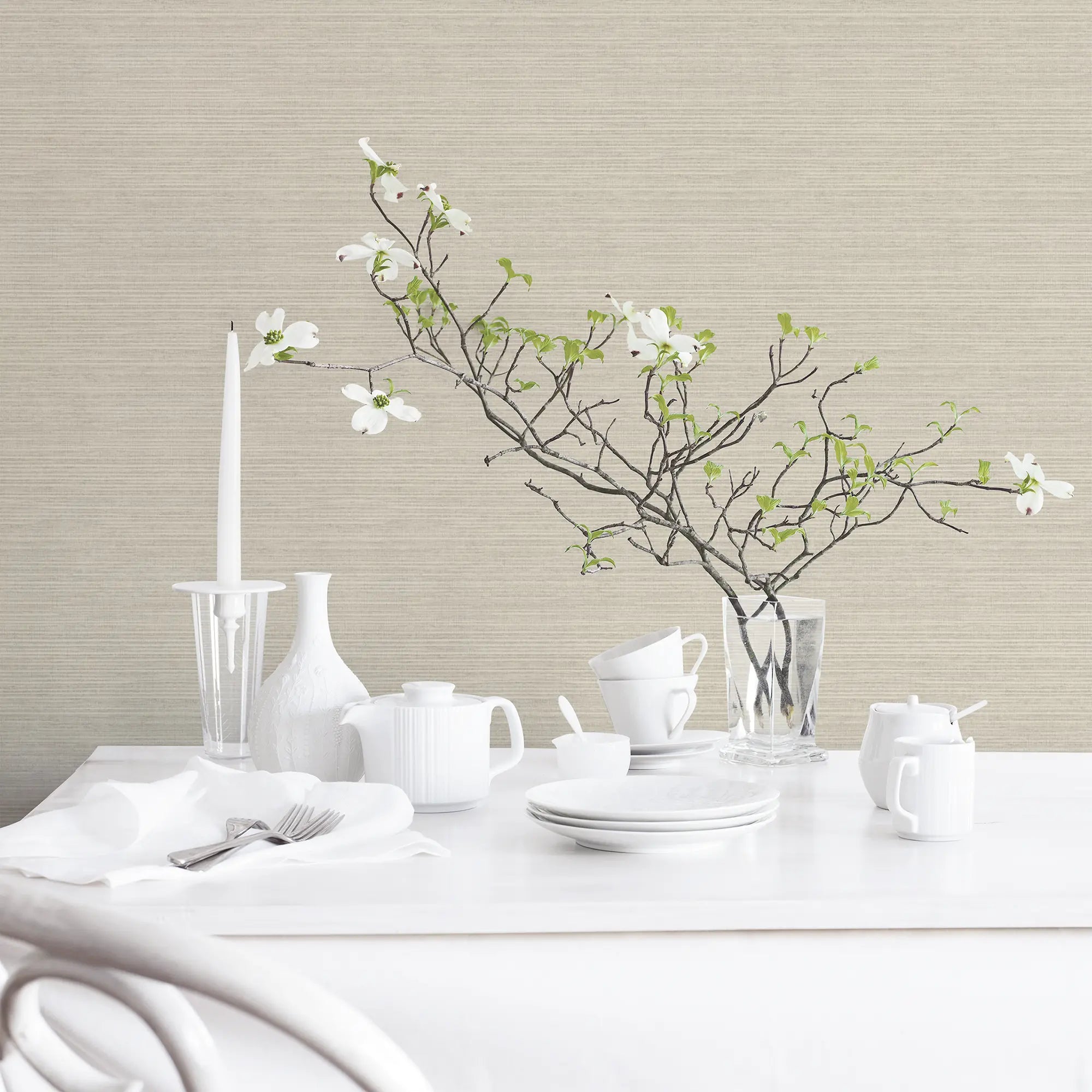 Et elegant spiseområde med Linen Texture - Sand tapet fra Nicetapet.dk, der matcher de hvide porcelænsservice og en vase med blomster.