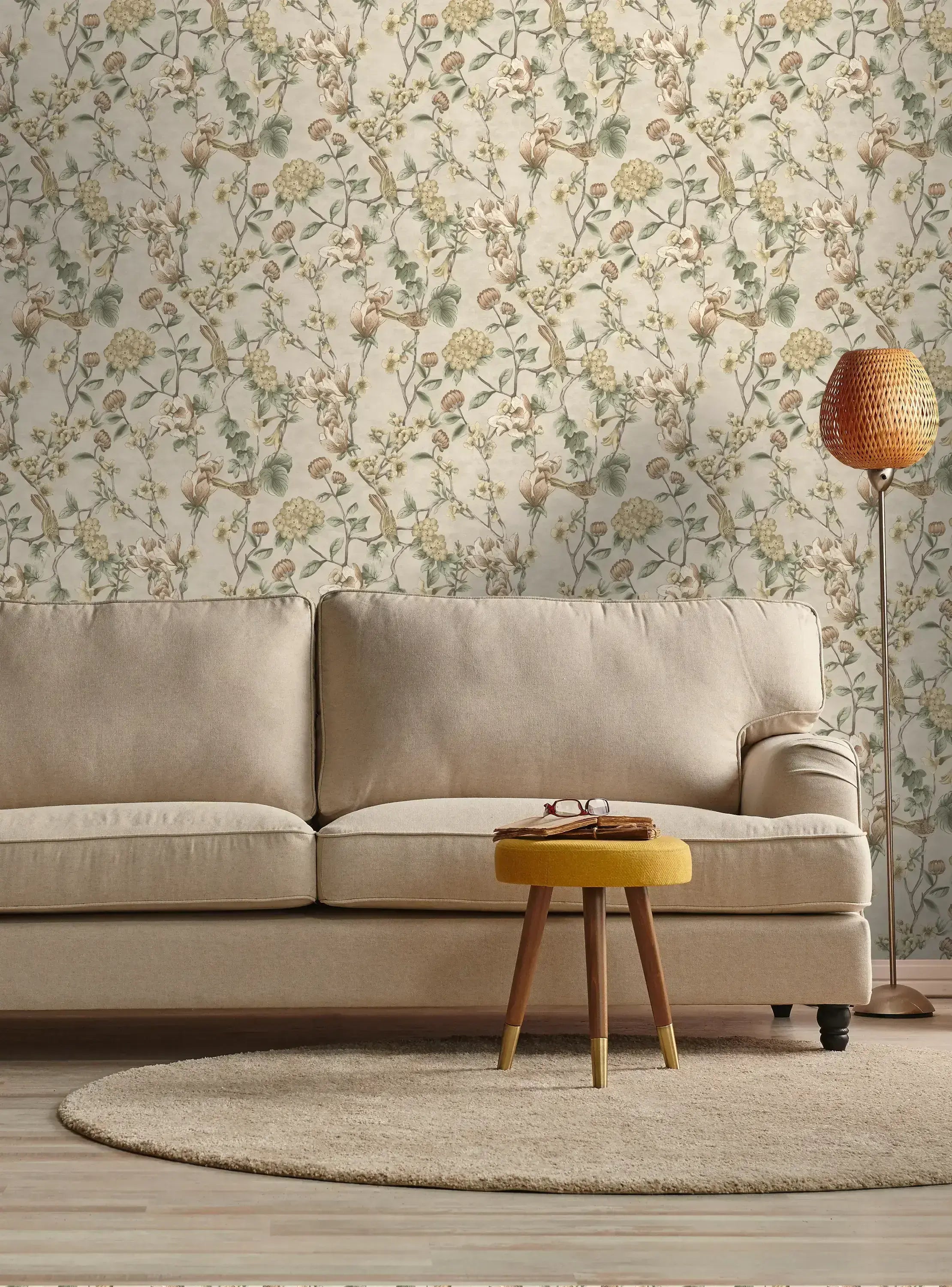 Stue med beige sofa og Nightingale - Cream tapet på væggen, med fugle og blomsterdesign