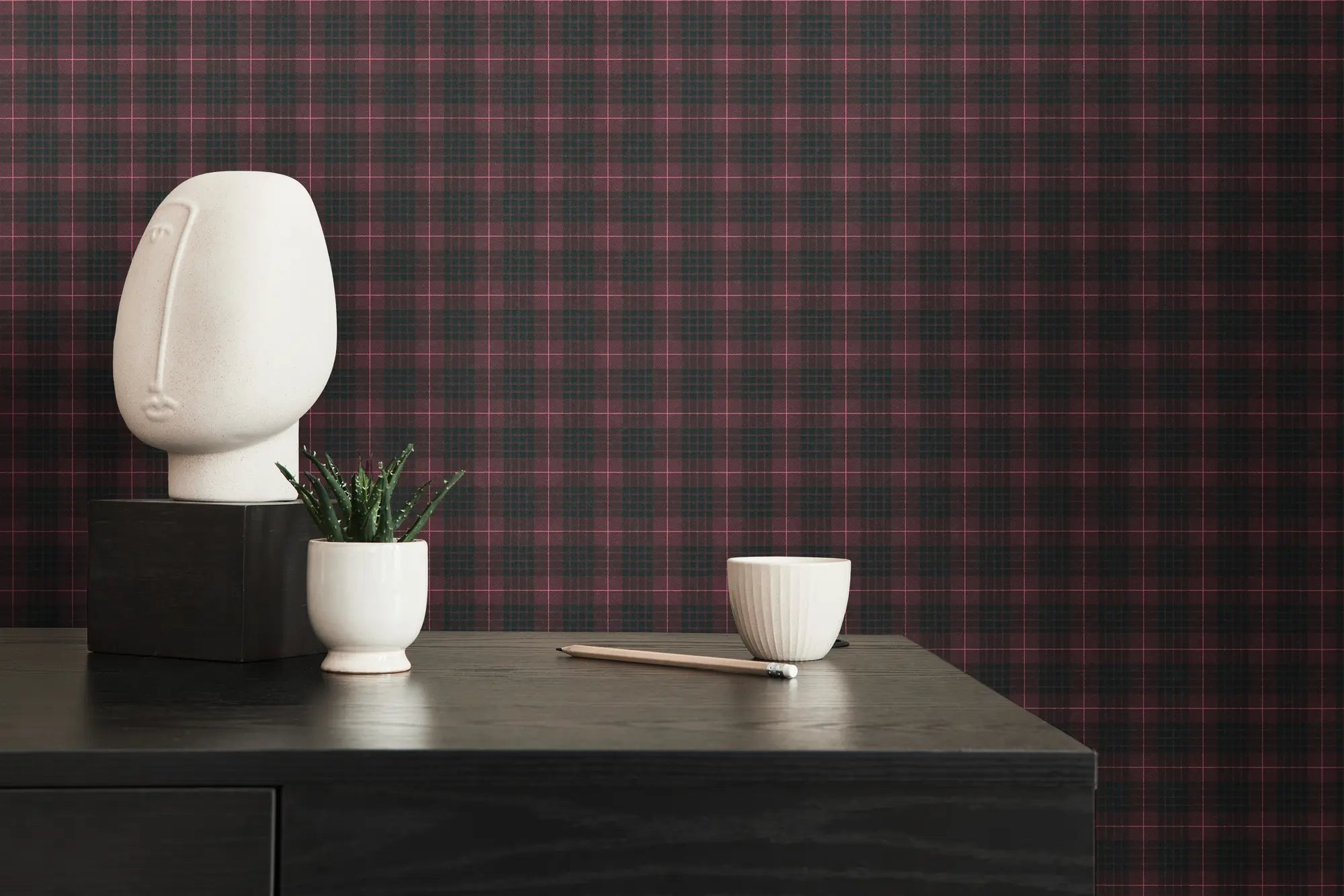 Interiørfoto med Plaid Reverie - Midnight Rose tapet på væggen, dekoreret med en skulptur og planter på en sort skænk.