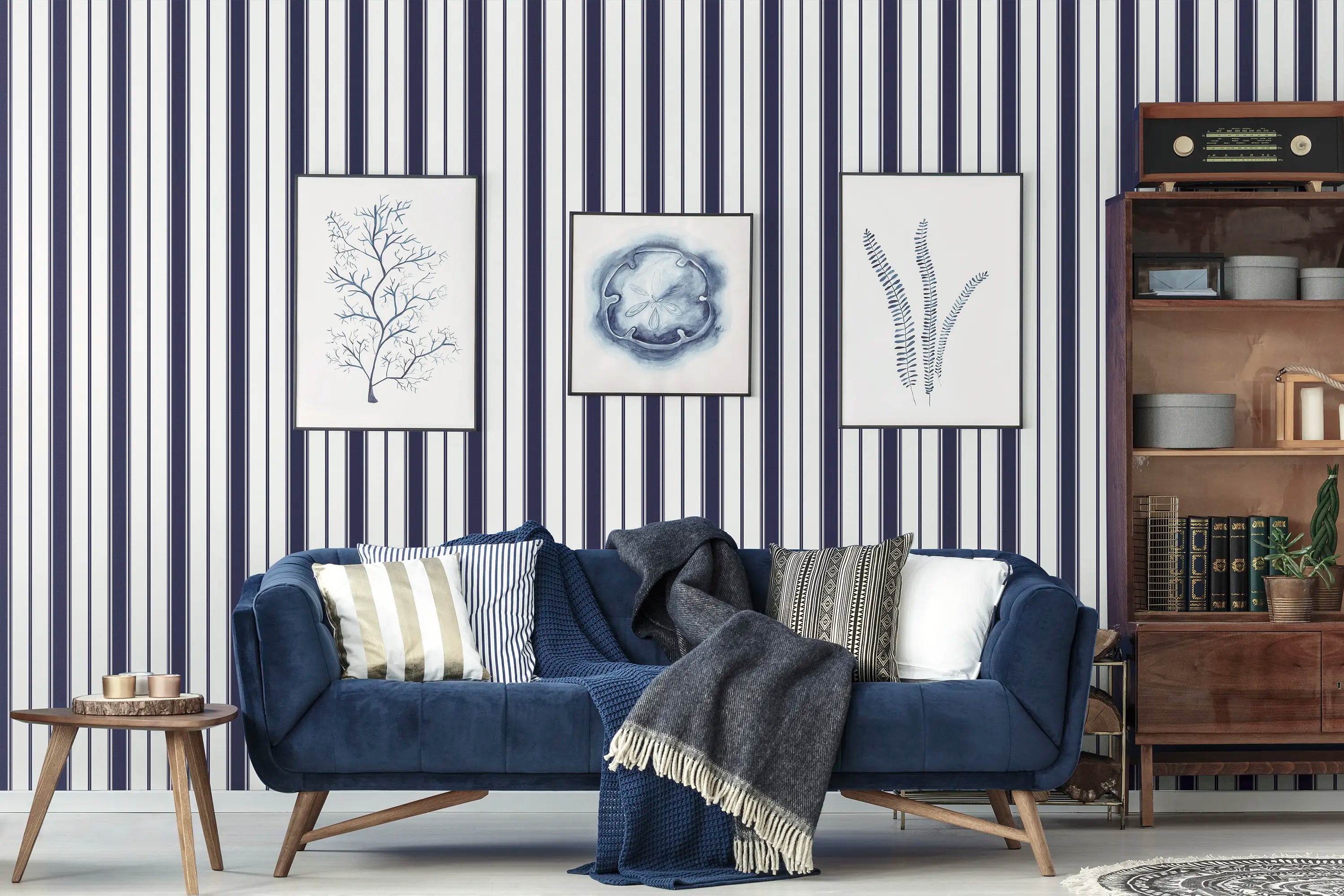 Refined Lines - Navy tapet i en stue med blå sofa, puder og indrammede billeder på væggen.