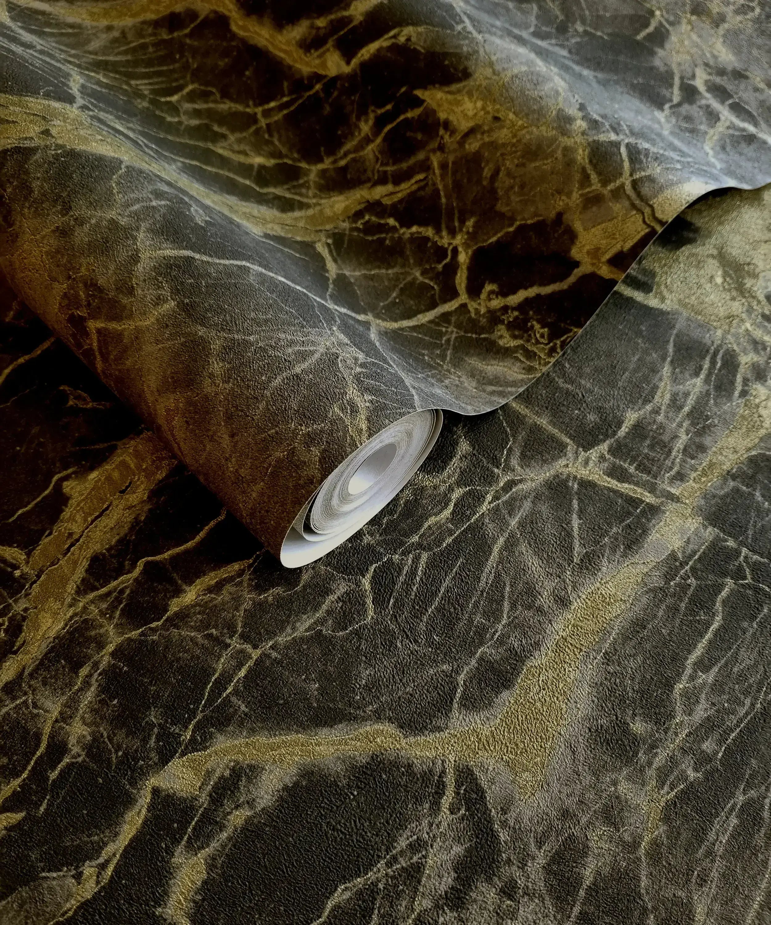 En rulle af Portoro Marble - Charcoal Gold tapet viser det gyldne og sorte marmormønster.