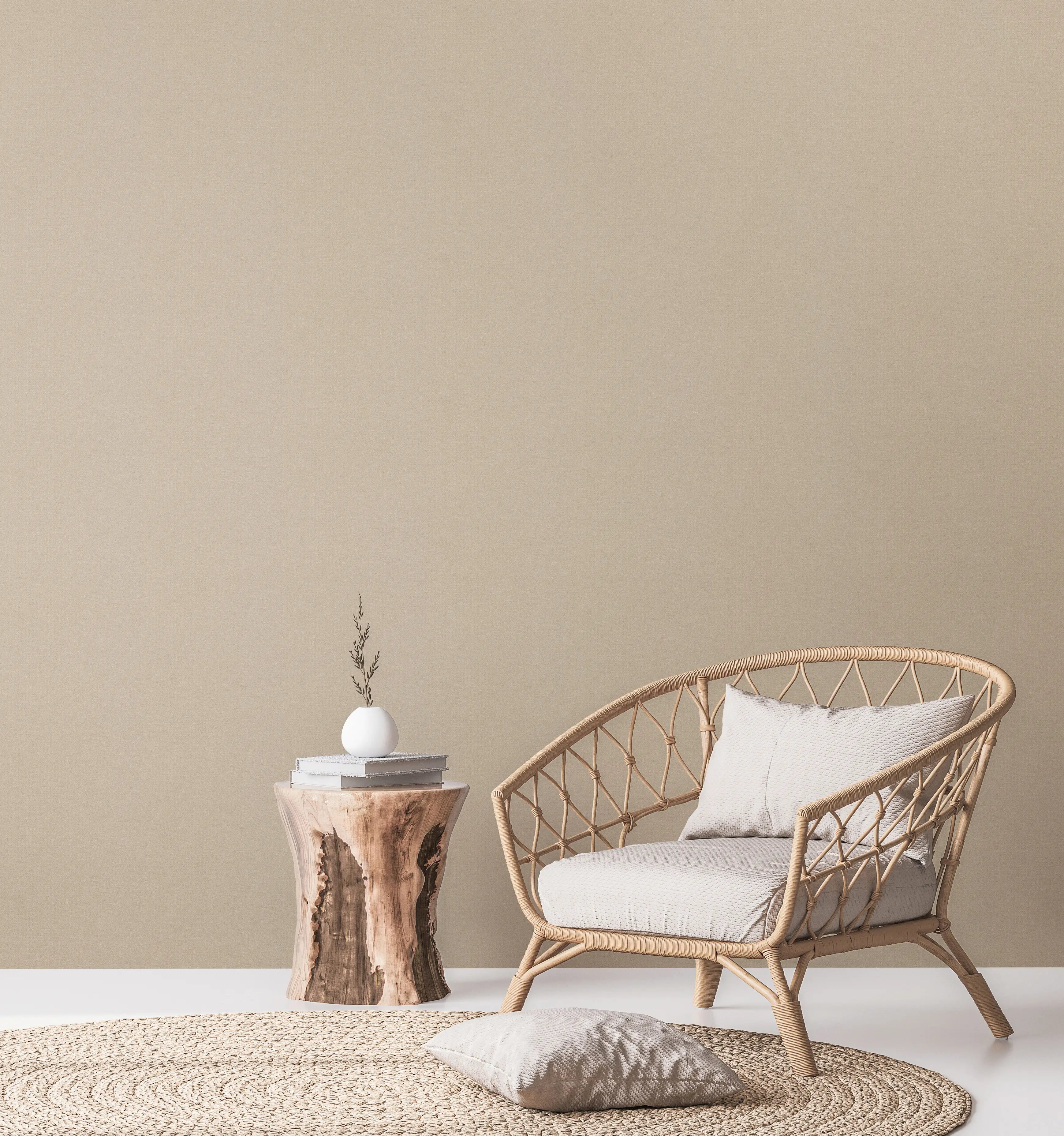 Stueindretning med Subtle Texture - Cream Sand tapet på væggen. Rattan stol, træbord og dekorationer fuldender looket.