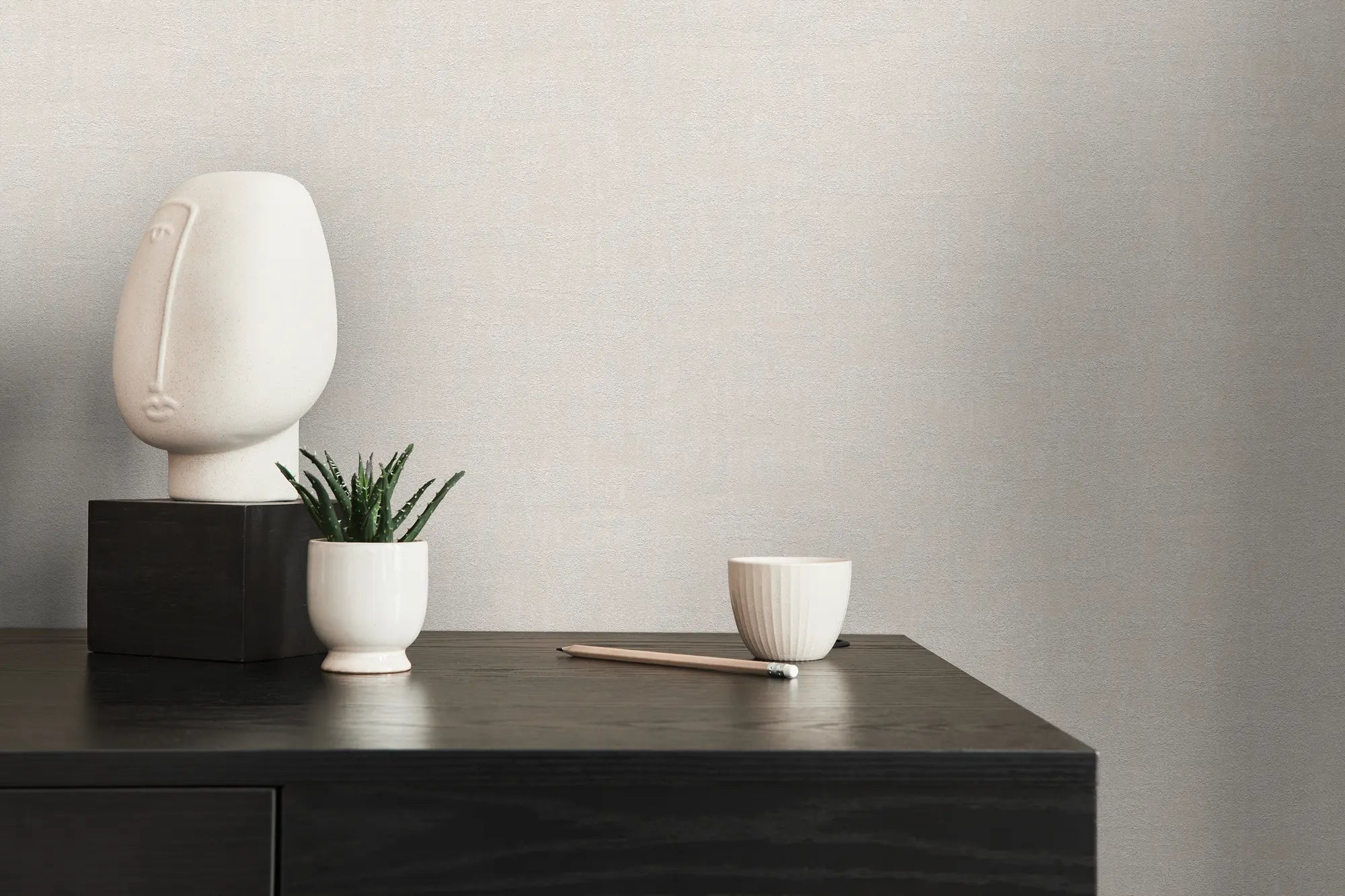 Indretningsbillede med Textured Elegance - Alabaster tapet som baggrund, prydet med en skulptur, en plante og en skål på en sort overflade.