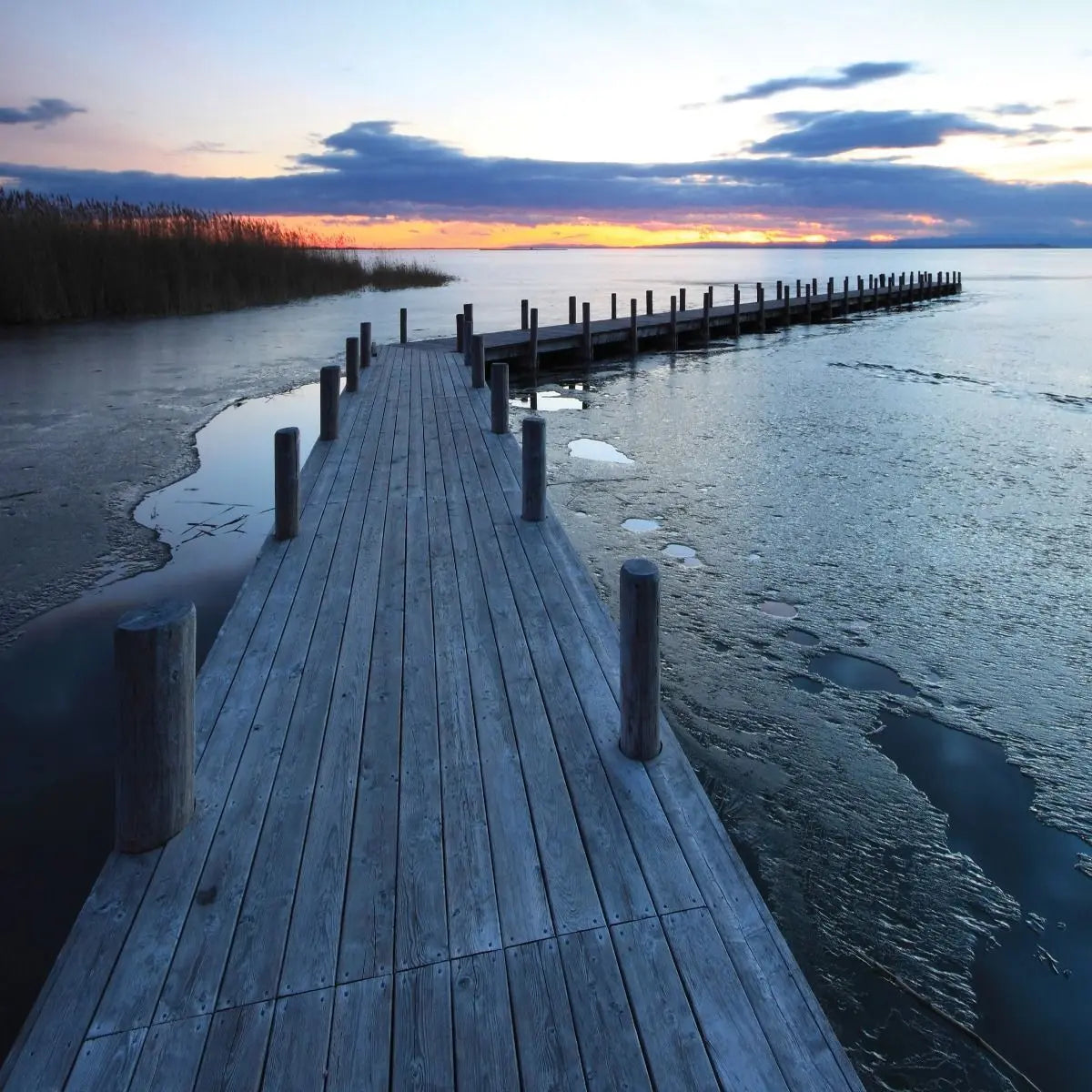 Billede 6 af Fototapet - Træbrygge ved solnedgang med delvist isdækket vand