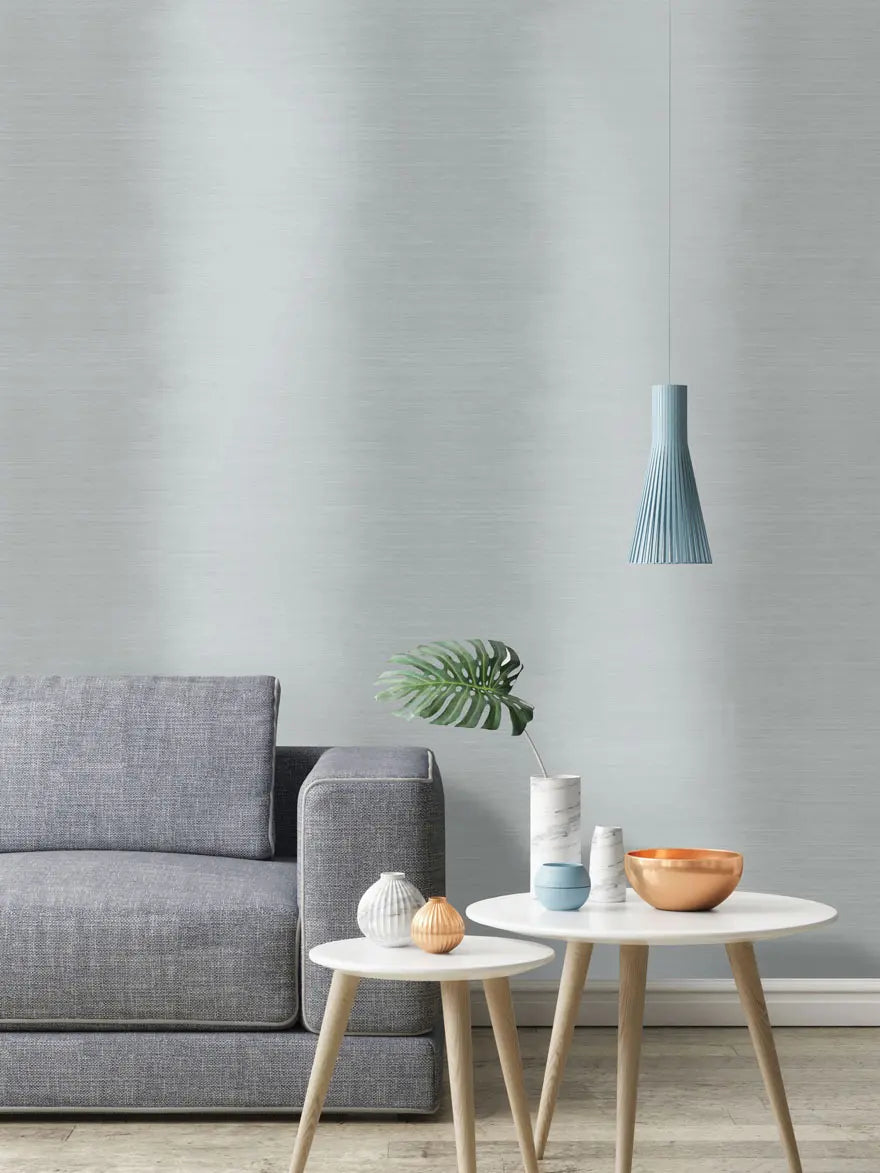 Vignette Stripe - Grey tapet i en moderne stueindretning med en grå sofa, blå lampe og små dekorative borde.