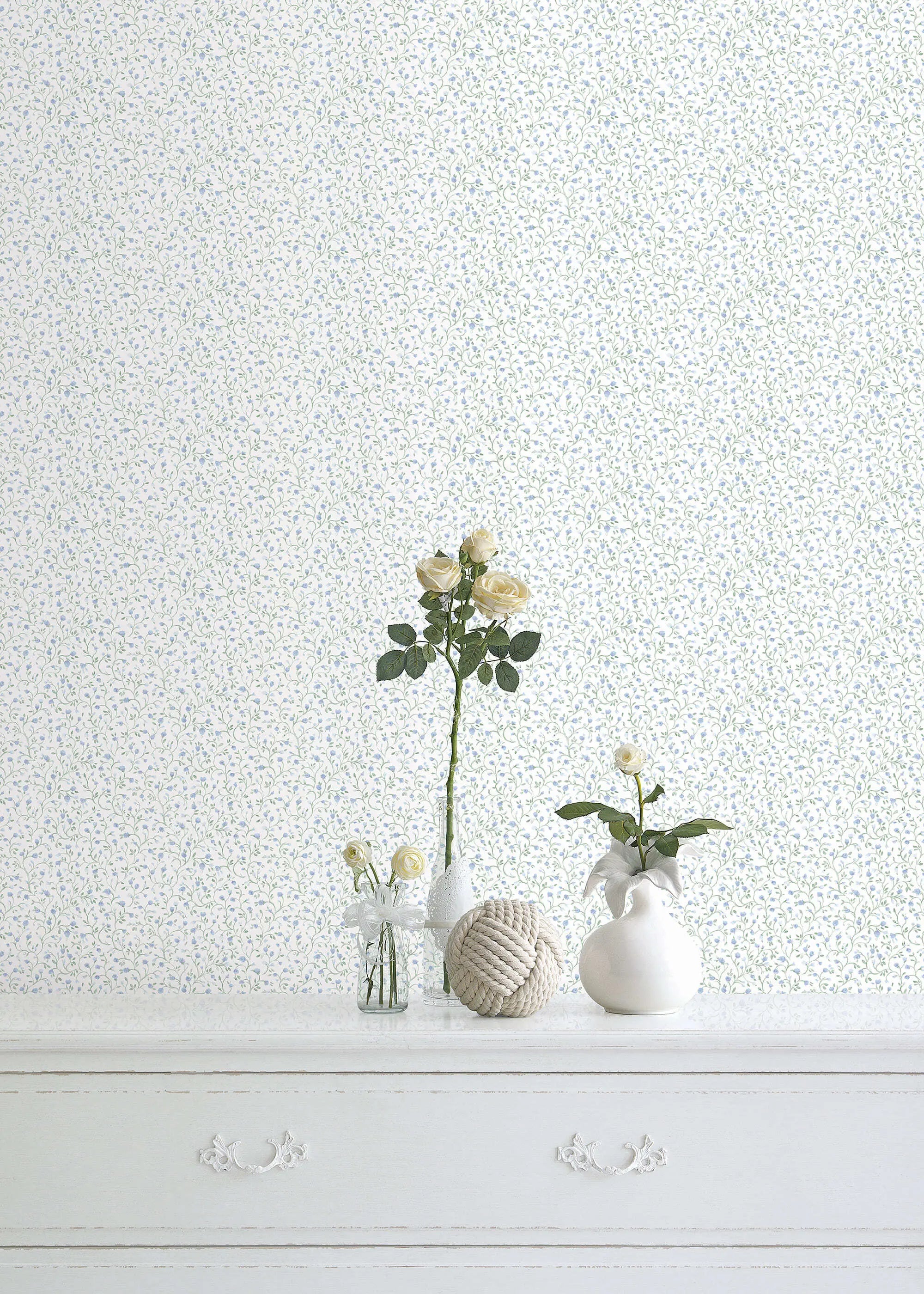 Whimsical Vines - Spring Green tapet i et rumindretning, der viser tapetet i baggrunden med dekorative genstande og blomsterarrangementer på en hvid kommode.